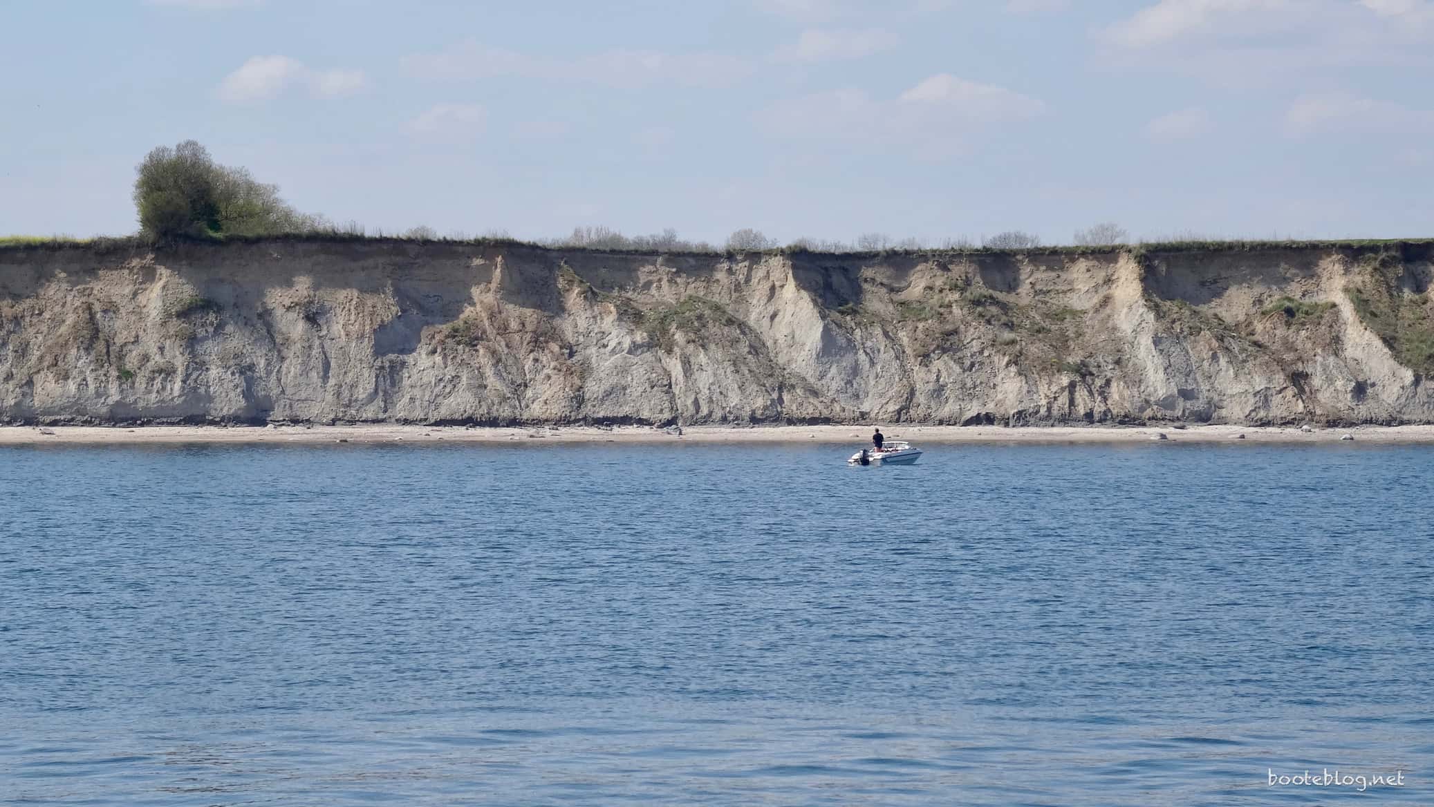 Ein Angler, der im kleinen Boot entspannt vor der Küste ankert.