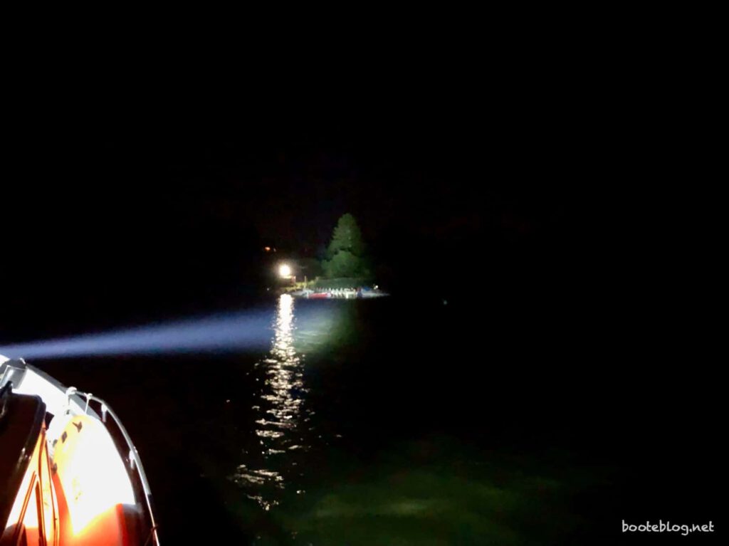 Suchscheinwerfer auf dem Boot leuchtet das Ufer an.