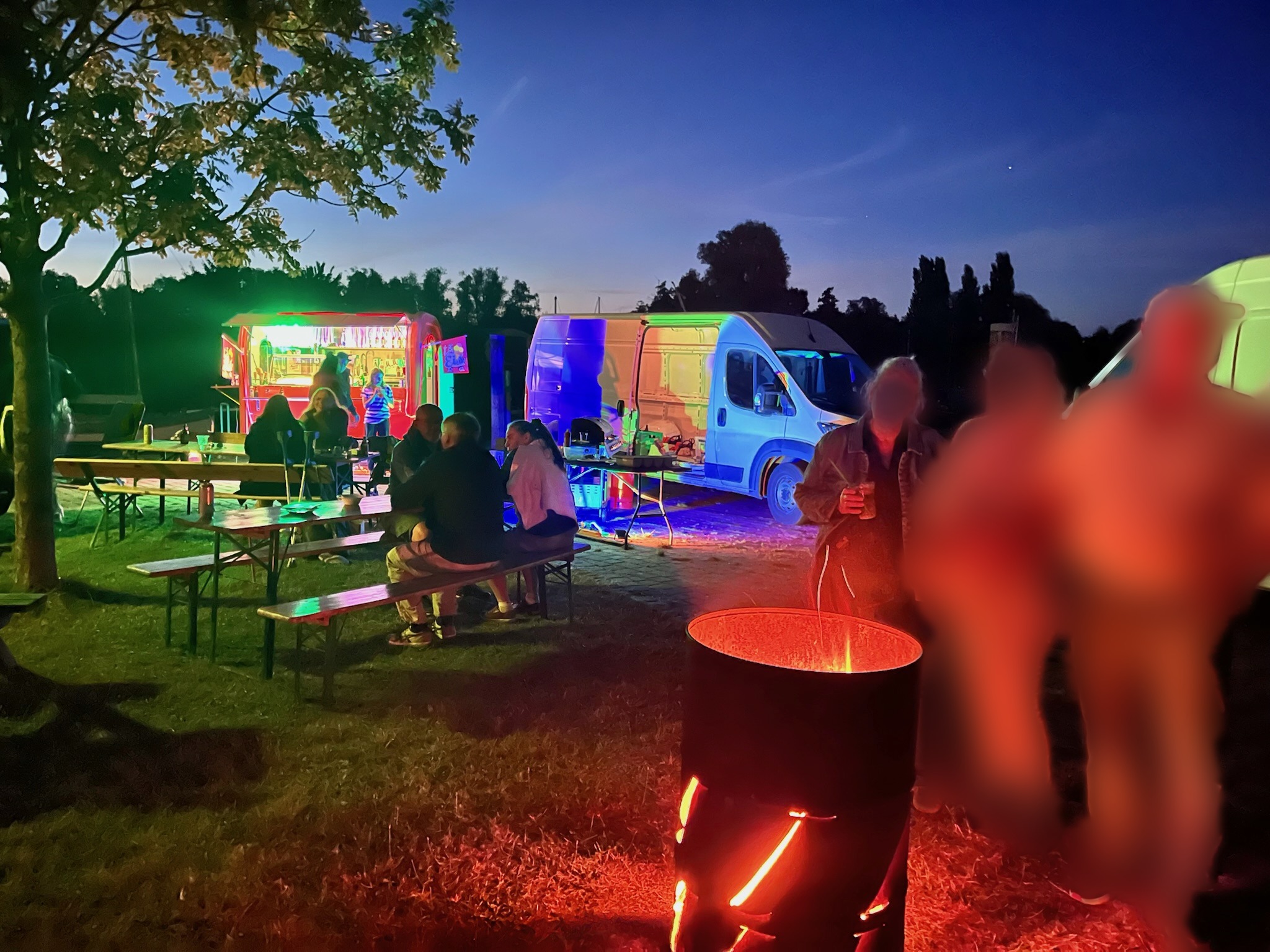 Abendliche Szene mit Foodtrucks und Feuerschale im alten Hafen (Personen anonymisiert)