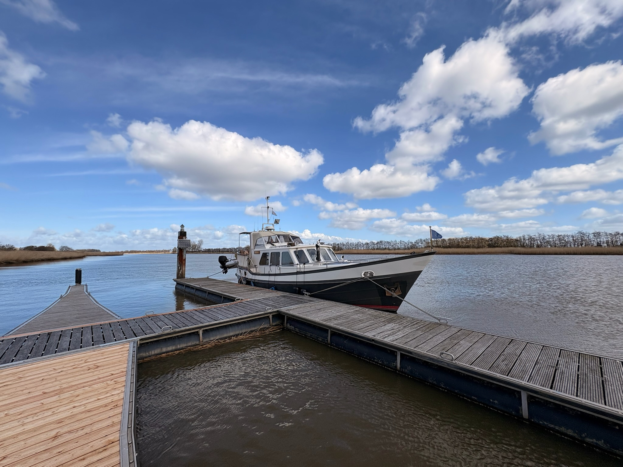 Motorboot an hölzernem Steg des Yachthafens Neuhaus, ruhiges Wasser