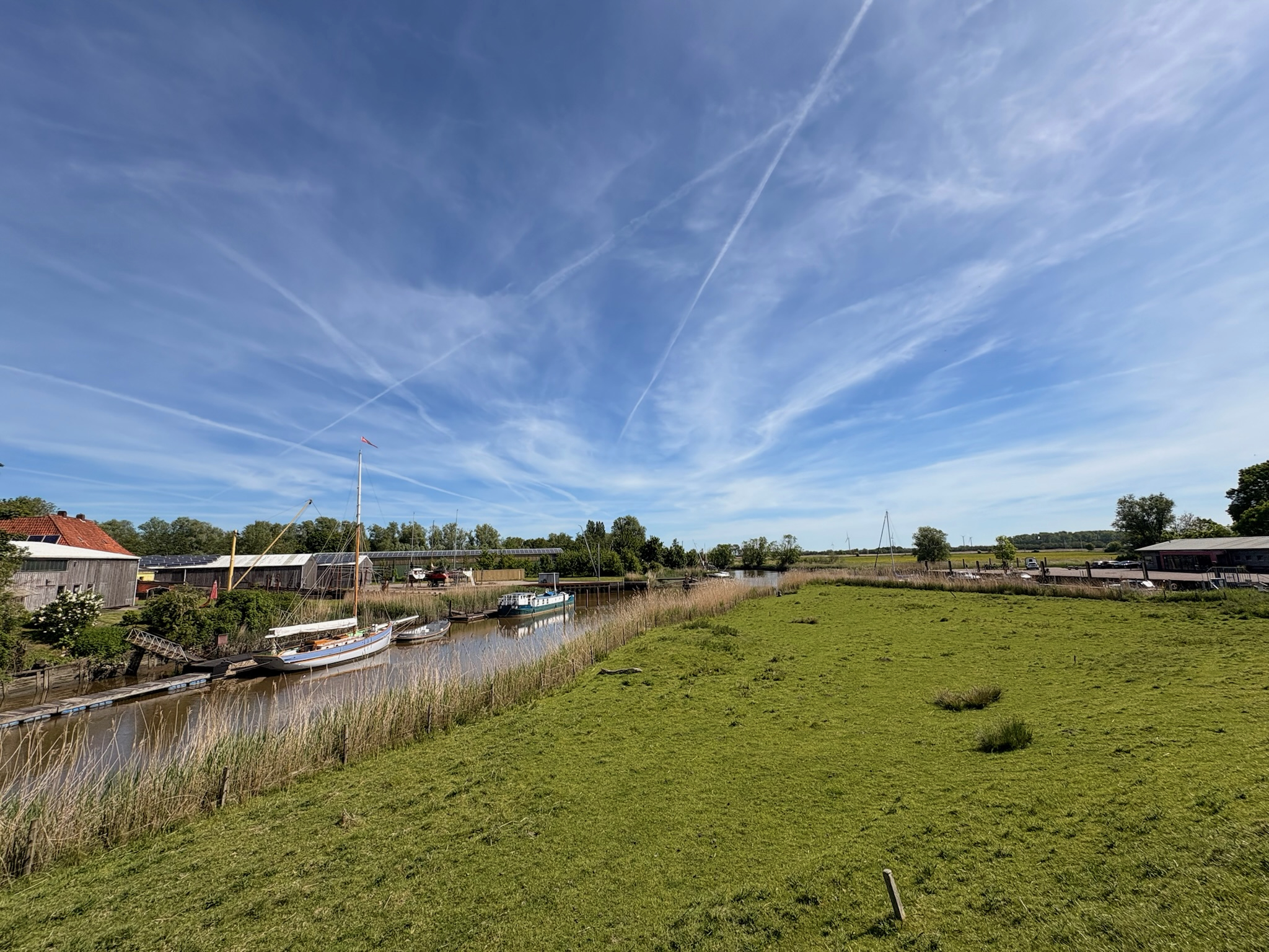 Kleiner Hafen mit Segelboot, Schilf und Holzsteg